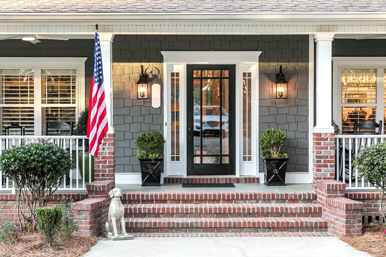 Front entry door to home with planters and large flag